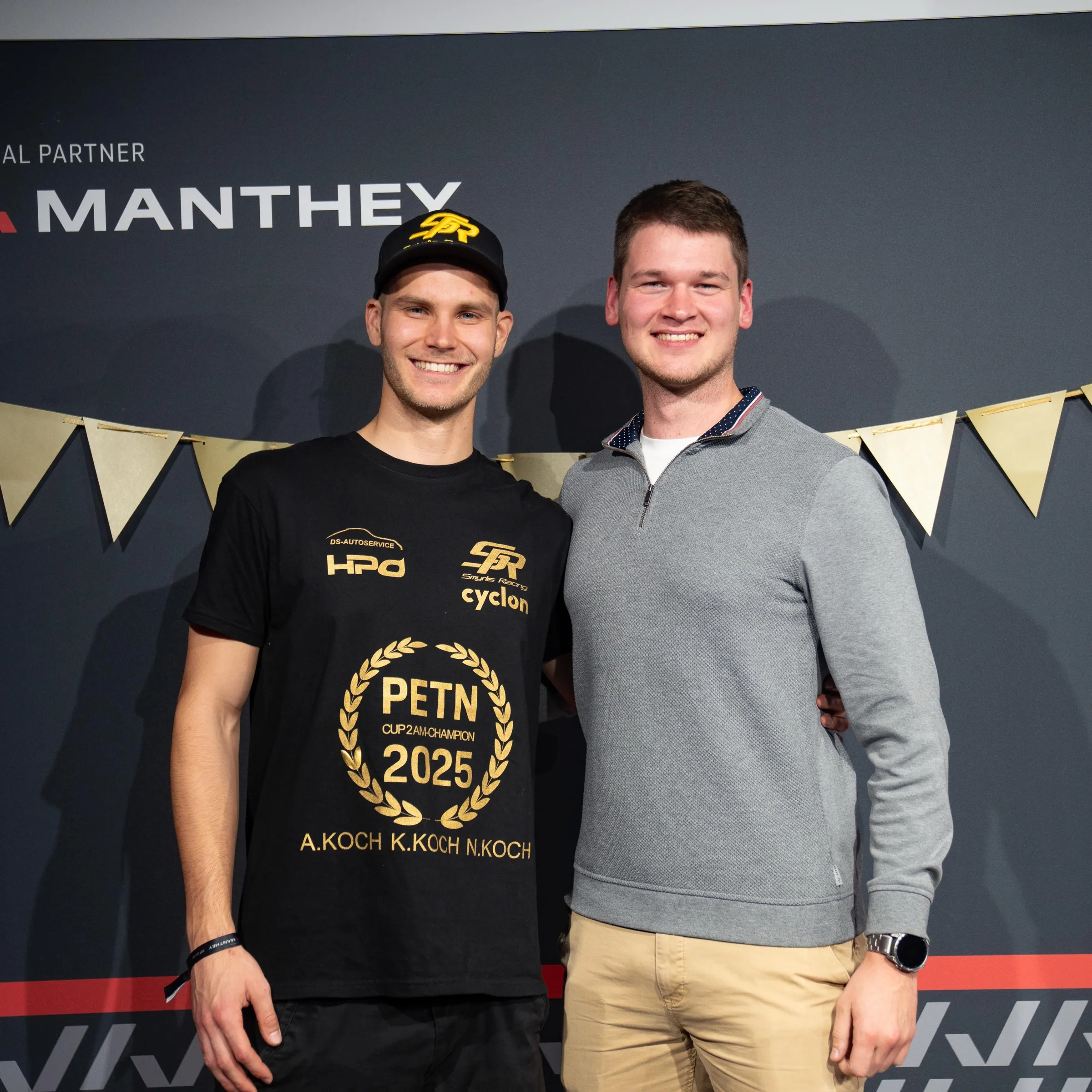 Rennfahrer Niklas Koch im Champion-Shirt des PETN Cup 2 (2025) lachend neben Pascal Kayser